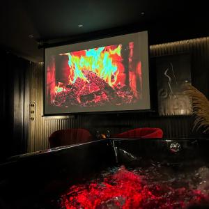 a projection screen with a fire in a room at BlackRoom Suite de Luxe 50 Nuances de grey in Le Havre