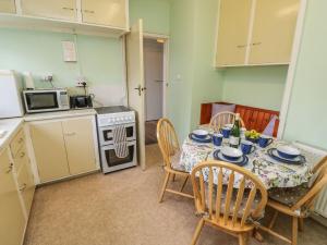 a kitchen with a table and chairs and a kitchen with a stove at The Shingles in Sandown