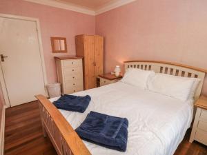 Un dormitorio con una cama blanca con toallas azules. en The Shingles, en Sandown