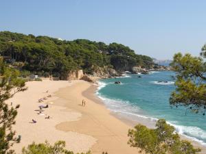 a beach with people laying on the sand and the ocean at Greenchalets Costa Brava Palamos in Palamós