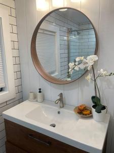 um lavatório de casa de banho com espelho e um vaso com flores em Shares Courtyard Luxury Apt - NEW! em Rockledge