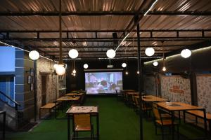 a room with tables and chairs and a projection screen at BACPAC MONKEY COLIVING in Visakhapatnam