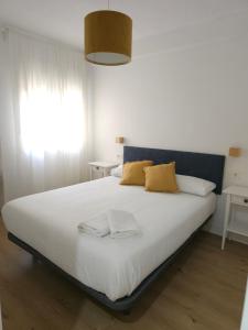 1 dormitorio con 1 cama blanca grande con almohadas amarillas en Exclusivo apartamento cerca de la playa, en Málaga