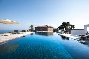 a swimming pool with an umbrella and some chairs at Momos Otel in Ayvacık