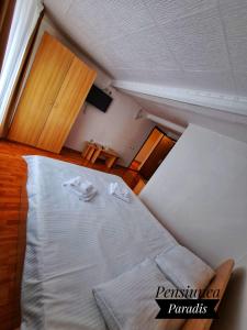 a bedroom with a white bed with two towels on it at Pensiunea Paradis in Buşteni