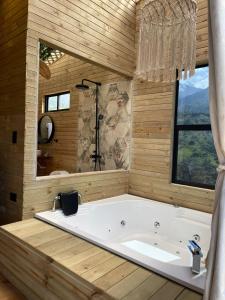 聖赫羅尼莫的住宿－Nalua Glamping y Hotel，窗户客房内的大浴缸