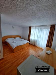 um quarto com uma cama e piso em madeira em Pensiunea Paradis em Buşteni