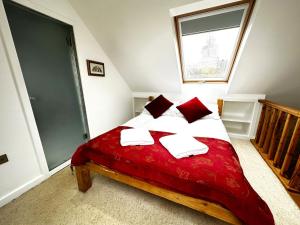 um quarto com uma cama grande com lençóis e almofadas vermelhas em Dove House Cottages - No 2 em Witney