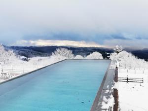 a swimming pool covered in snow with mountains in the background at Wellness hotel V Nebi in Kořenov