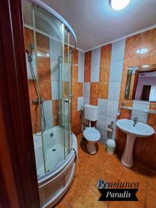 uma casa de banho com um chuveiro, um WC e um lavatório. em Pensiunea Paradis em Buşteni