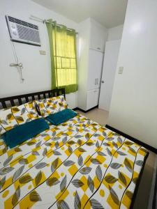 a bedroom with a bed with a yellow and white comforter at tranisient house @camella villa kanangga butuan city in Butuan