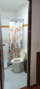 a bathroom with a toilet and a shower curtain at Hotel Habitat in Ibagué