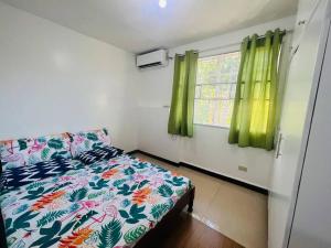 a bedroom with a bed and a window with green curtains at tranisient house @camella villa kanangga butuan city in Butuan