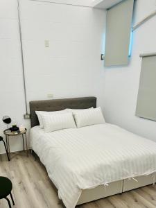 a white bedroom with a large bed with white sheets at Inside the alley in Tainan