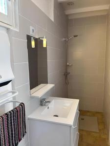 uma casa de banho branca com um lavatório e um espelho em Camping des Bains em Saint-Honoré-les-Bains