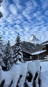 a snow covered building with a mountain in the background at Modernes Studio Zermatt in Zermatt