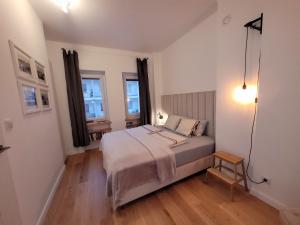 a small bedroom with a bed and two windows at SmileApartment Partyzantów in Gdynia