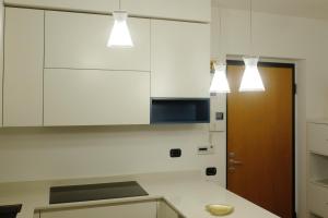 une cuisine avec des placards blancs et des lumières au-dessus d'un comptoir dans l'établissement Orea Spiti - Modern Oasis Near Milan, à Assago