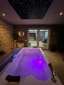 a large bath tub with purple lighting in a room at Bed & Wellness Chinel Luxe vakantiehuis met Sauna's en Bubbelbad in Sint Annaland