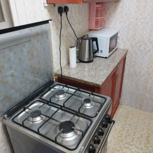 La cocina está equipada con fogones y microondas. en العين الهيلي مصباح بيت 11, en Al Ain