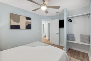 a white bedroom with a bed and a ceiling fan at Red Neptune by Nautical Properties in Panama City Beach