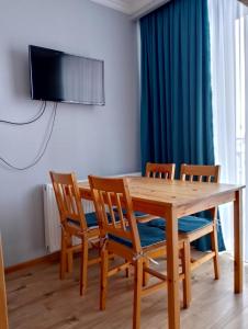 a wooden table with four chairs and a television on a wall at New Gudauri Loft #1,Room 411, 412 in Gudauri