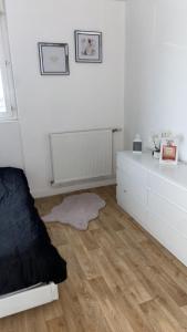 a white bedroom with a bed and a wooden floor at Appartement proche aéroport Beauvais-tille in Beauvais