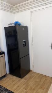 a black refrigerator in a corner of a room at Appartement proche aéroport Beauvais-tille in Beauvais