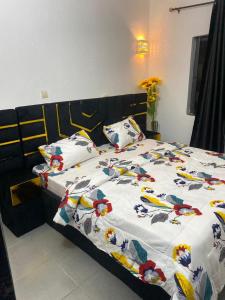 a bed with a white comforter with birds on it at Charly-chic@ in Cotonou