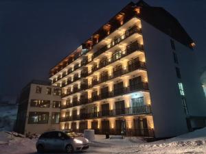 科帕奧尼克的住宿－President Kop A4，一座大建筑,有一辆汽车停在雪中