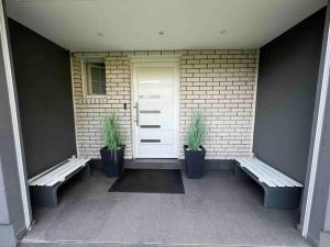 un porche con 2 bancos y una puerta blanca en Schönes 2 Zimmer Apartment an der Stadt Grenze en Blankenfelde