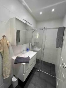 baño blanco con ducha y lavamanos en Schönes 2 Zimmer Apartment an der Stadt Grenze en Blankenfelde