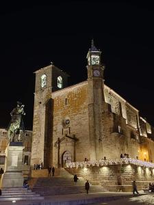 un grande edificio in pietra con torre dell'orologio di notte di Conde de la Encina a Trujillo