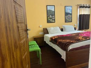 sypialnia z łóżkiem i zielonym stołkiem w obiekcie Crystal homestay w mieście Utakamand