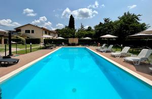 a large blue swimming pool with chairs and umbrellas at Oasi di Agilla in Panicarola