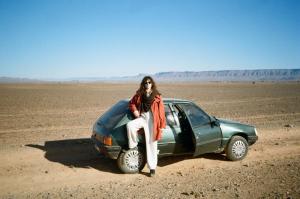 Una mujer sentada encima de un coche en el desierto en Tinfou desert camp, en Brija