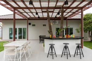 a patio with a bar and stools under a pergola at Houses of Sunny in Bang Sare