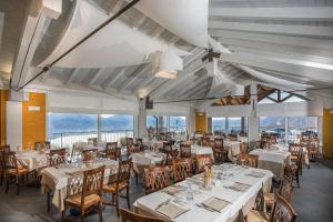 een eetkamer met witte tafels en stoelen en ramen bij Residence Usignolo in Trarego