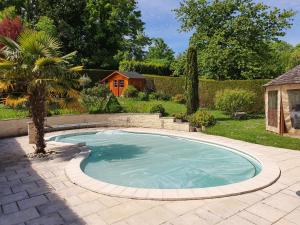 una piscina en un patio con una palmera en Spacieuse chambre, sdb privative et piscine chauffée, en Oinville-sur-Montcient