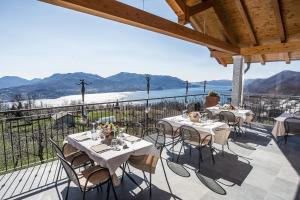 eine Terrasse mit Tischen und Stühlen mit Bergen im Hintergrund in der Unterkunft Residence Usignolo in Trarego