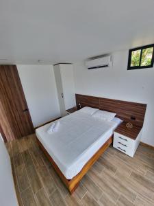 a bedroom with a large white bed with a wooden headboard at Villa El Bosque Dorado in Fortuna