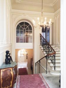 einen Flur mit einer Treppe und einem Kronleuchter in der Unterkunft Wienerwald Residenz in Baden