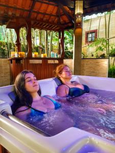 two women in a jacuzzi in a resort tub at Pousada e SPA Canto do Mar in Guarujá