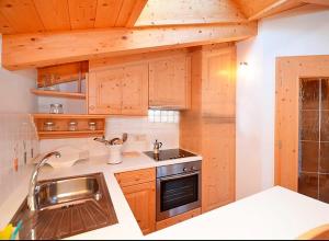 a kitchen with wooden cabinets and a sink at Housetirol in Valdaora di Sotto