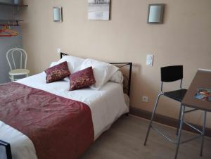 1 dormitorio con 1 cama, 1 mesa y 1 silla en Hôtel Moderne, en Prades-dʼAubrac