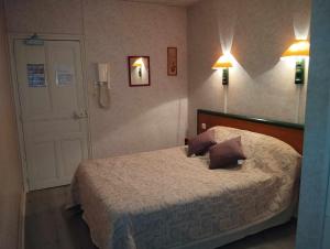 a bedroom with a bed with two pillows on it at Hôtel Moderne in Prades-dʼAubrac