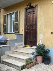 a house with a wooden door and stairs with plants at La casa di Eva e Zoe in Albano Laziale