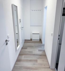un couloir vide avec des murs blancs et du parquet dans l'établissement Ferienwohnung Lippstadt, à Lippstadt