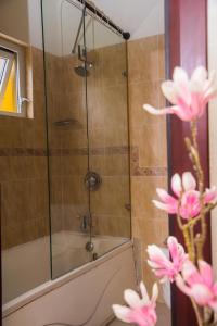 y baño con ducha y flores rosas. en MARIBELLA@CRYSTAL COVE OCHO RIOS, en Stanmore Grove