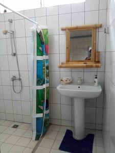 uma casa de banho com um lavatório e um espelho em Meri Lodge Huahine (Mamado’s House) em Fare